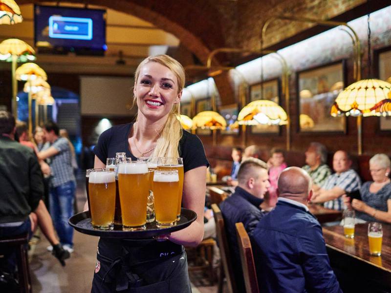 smiling waitress carrying plenty of beers
